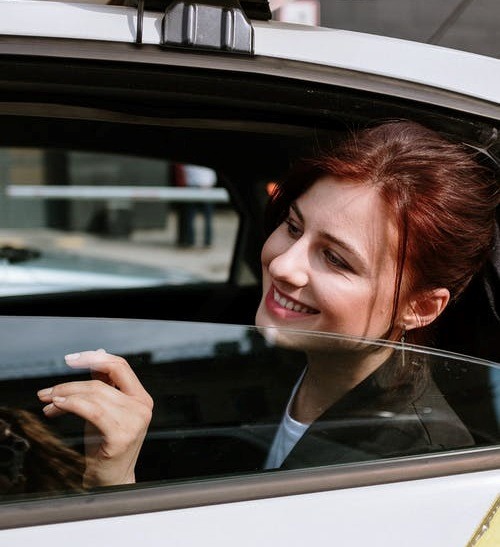 A woman smiling while travelling in a taxi