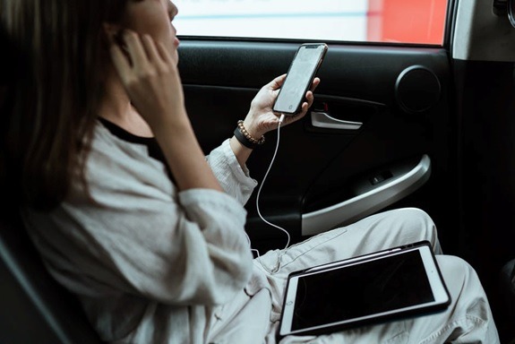 A woman sits in the back of a taxi cab during her travels.