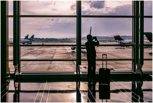 A man standing at the airport with luggage waiting for an airport taxi service