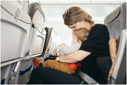A mother sitting with a toddler on a plane seat