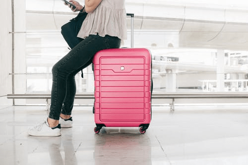 a person sitting on a pink-colored suitcase