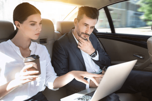 Two executives working on their laptop in the car