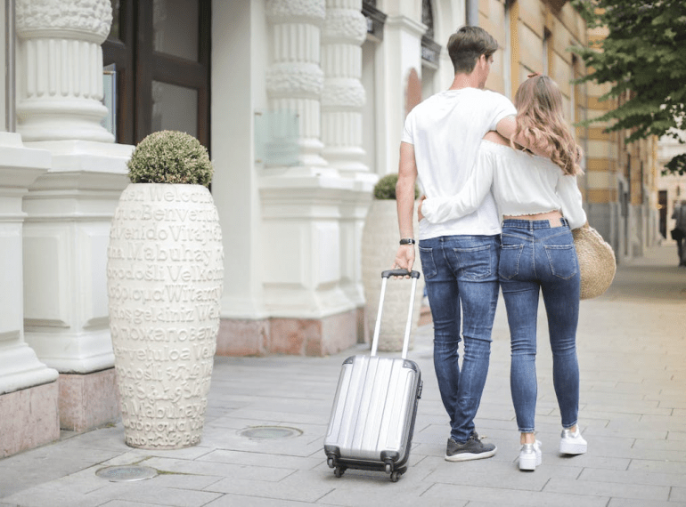 Couple with a suitcase walking down the street.