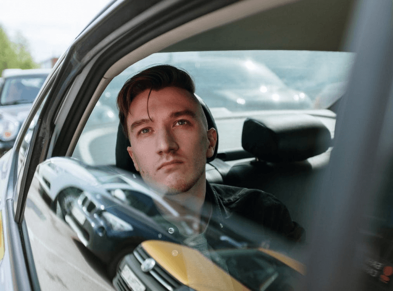 Man sitting inside a taxi, looking out the window.