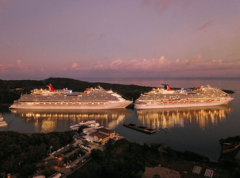 Two cruise ships docked near an island.