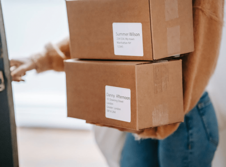 A woman carrying boxes and entering the post office