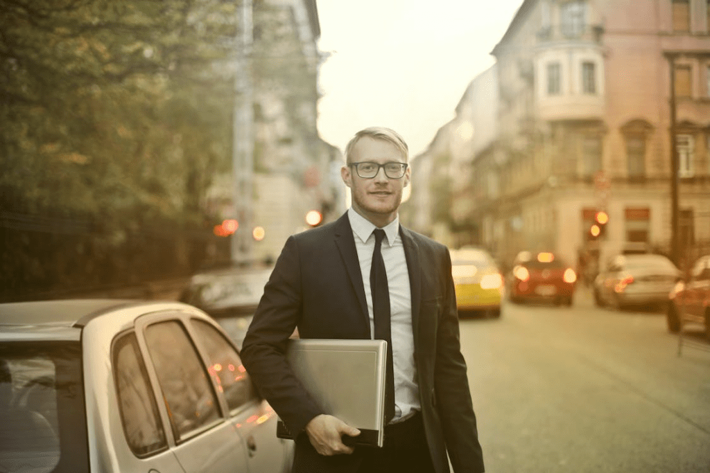 Determined smiling businessman with a laptop on the street