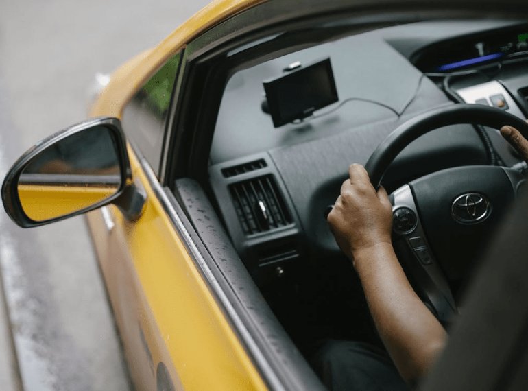 Faceless person driving a contemporary cab in the city