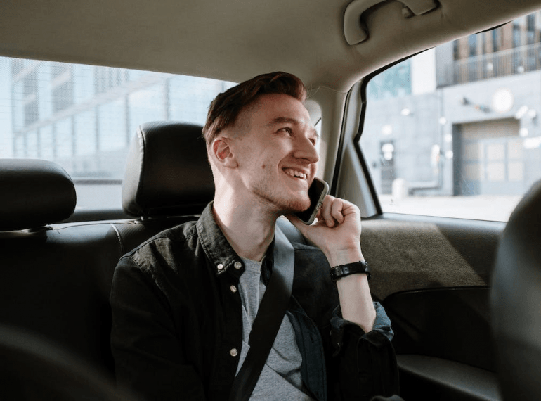 Man in a black jacket sitting inside a car