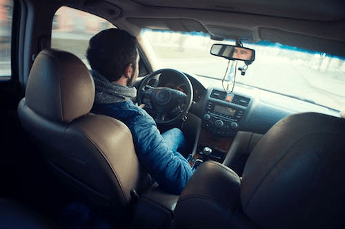 Man wearing a blue jacket sitting inside the car while driving