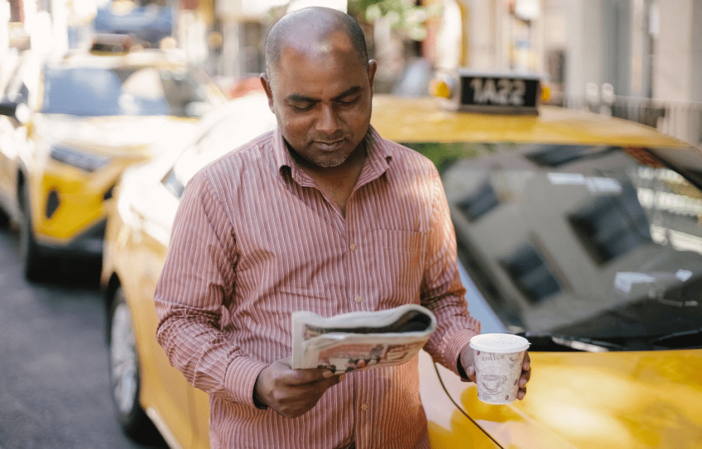 Man with coffee and newspaper near the cab