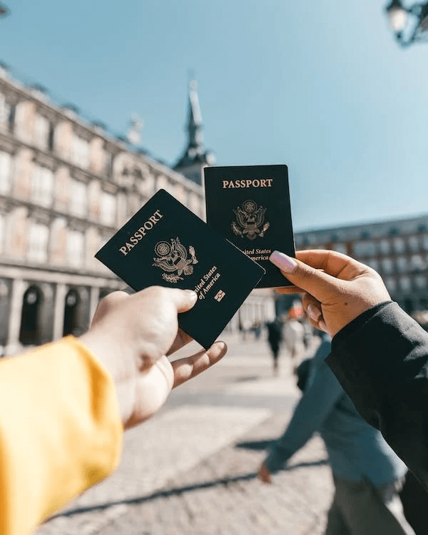 An image of two anonymous tourists showing their passports on the street on a sunny day