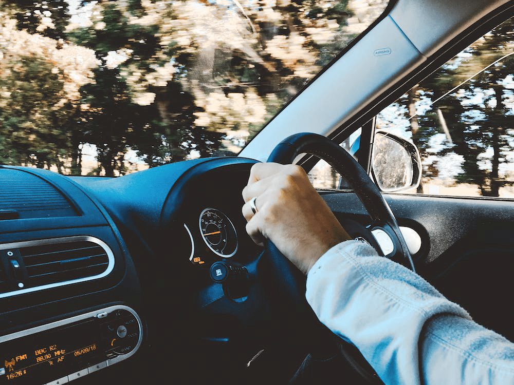 An image of a person holding black steering wheel in car