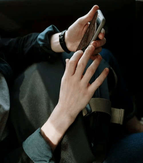 An image of a person in black jacket using their phone in the car