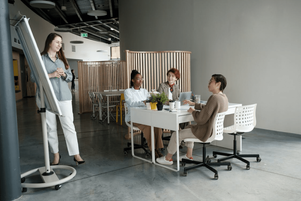 An image of a group of people in a discussion during a meeting as they stare at a white board