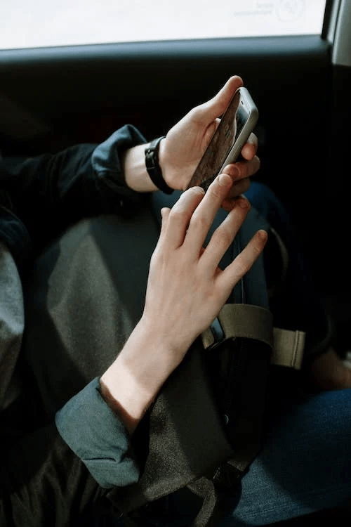 An image of a person in black jacket using their phone in the car