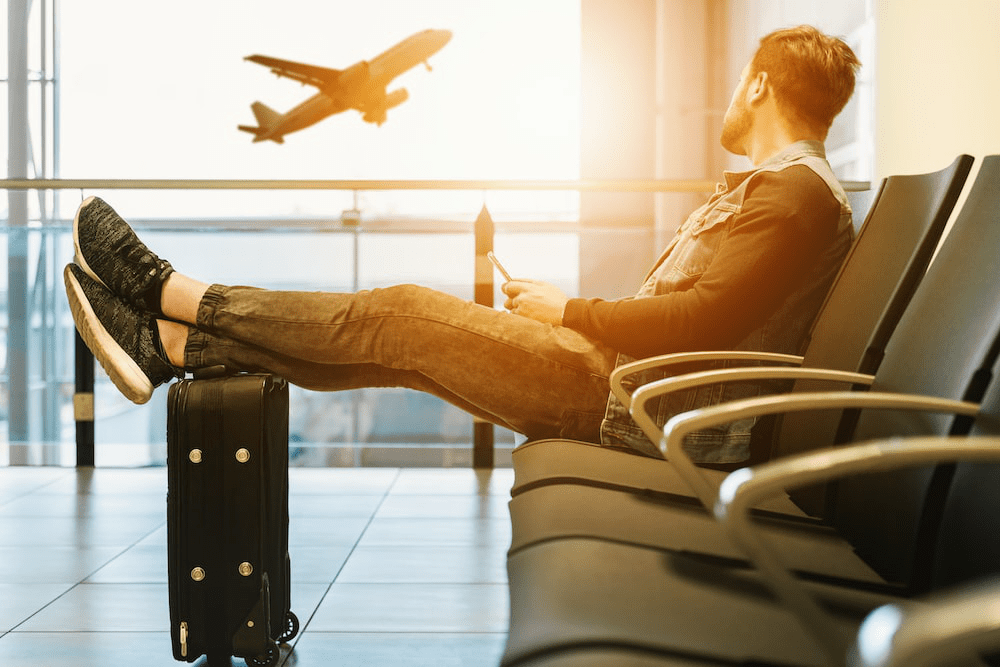 An image of a man sitting in an airport with a suitcase