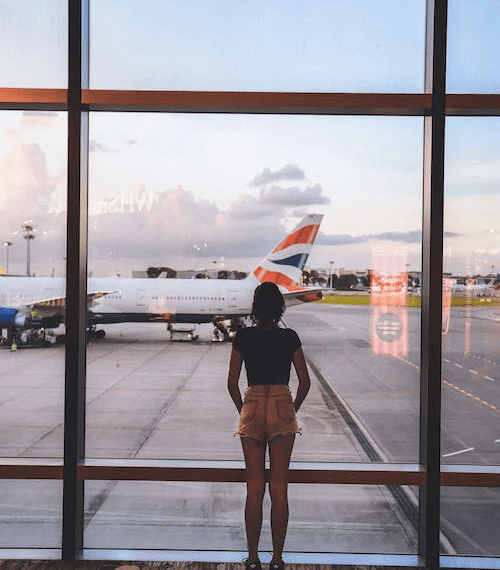 An image of a woman standing near a glass wall inside an airport